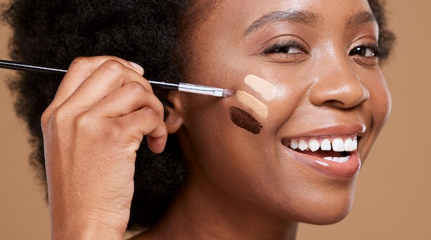Rosto de mulher negra e sorriso para cosméticos de base de maquiagem ou cuidados com a pele contra um fundo de estúdio marrom Retrato de mulher africana feliz aplicando produto de beleza cosmético com pincel para toner de pele