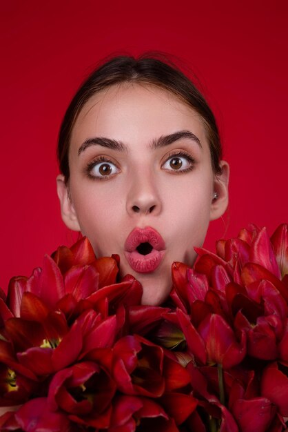 Rosto de mulher surpresa com flores menina de beleza com tulipa linda mulher sensual segura buquê de tulipas