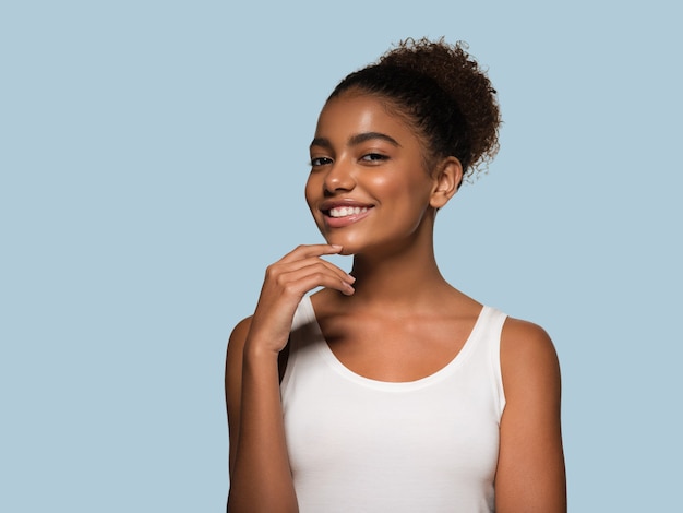 Rosto de pele negra de mulher beleza sorrindo modelo tocando seu rosto. cor de fundo. azul