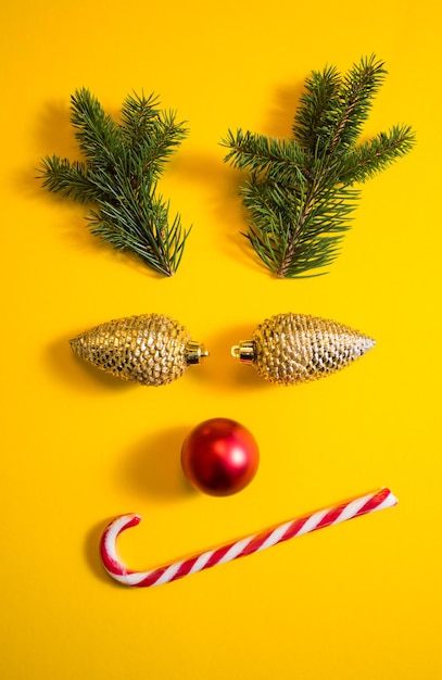 Rosto de rena de Natal festivo e fofo, organizado a partir de galhos de pinheiros e pirulito usado como parte do rosto Inspirtaion de férias de inverno Mock up para fundo amarelo de cartão de felicitações