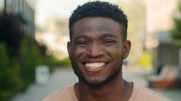 Rosto de rosto masculino de perto expressão de felicidade retrato afro-americano feliz sorridente cara na cidade rir reação engraçada desfrutar de homem biracial sorriso dentes brancos serviço dentário odontologia medicina ao ar livre
