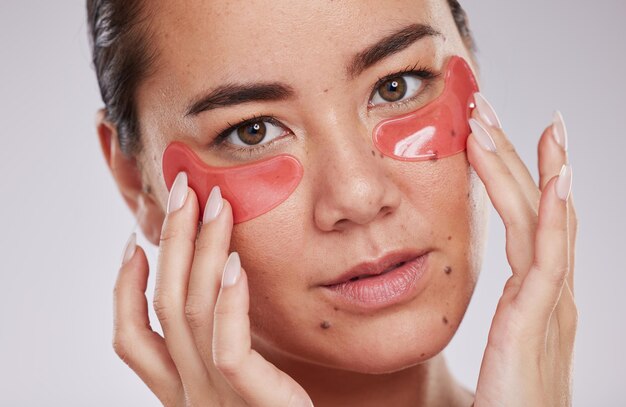 Foto rosto de skincare e mulher com tapa-olhos em estúdio isolado em um fundo cinza cosméticos dermatológicos e retrato de jovem modelo feminino com almofadas faciais ou produtos para beleza ou tratamento de pele