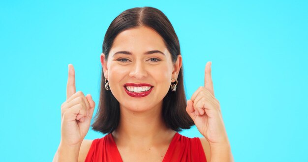 Rosto de sorriso e mulher em fundo azul apontando para notícias no estúdio de cor de maquete Retrato de modelo feminino promoção de publicidade colocação de produto e apresentação de oferta comercial em breve