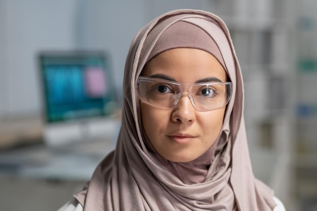 Rosto de uma jovem médica muçulmana em hijab e óculos de proteção