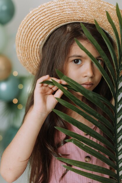 Rosto de uma menina cercada por folhas tropicais. Retrato de um lindo bebê moreno