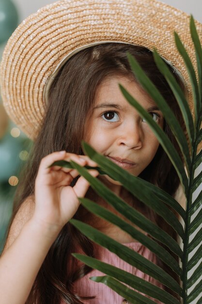 Rosto de uma menina cercada por folhas tropicais. Retrato de um lindo bebê moreno
