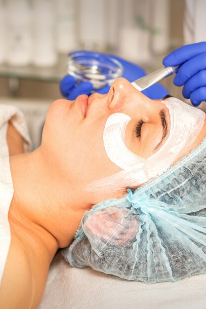 Rosto descascando na esteticista. tratamento facial. a esteticista aplica uma máscara facial de limpeza na paciente do sexo feminino.