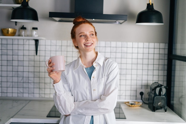 Rosto fechado de uma mulher sorridente feliz bebendo café quente em casa olhando para longe em câmera lenta