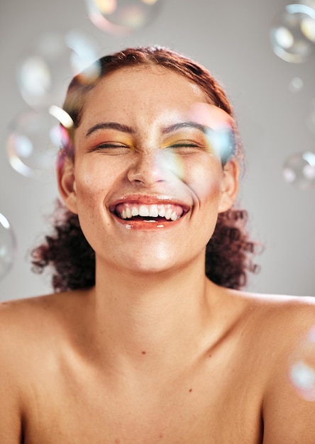 Foto rosto feliz de bolhas e mulher de beleza em estúdio para cosméticos para a pele pele natural e dermatologia maquiagem facial saúde e bem-estar da pessoa modelo cômica com produto corporal de luxo brilho e paz