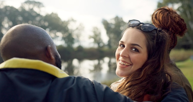 Rosto feliz e mulher com amigos no lago acampando na natureza ou em grupo rindo e se unindo em um piquenique ao ar livre no parque retrato de menina ou sorriso em conversa reunião social ou relaxar na floresta