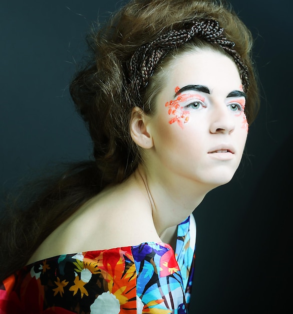 Rosto feminino jovem com maquiagem multicolorida de moda brilhante
