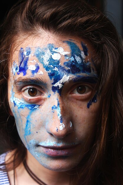 Foto rosto pintado com cores acrílicas azuis e brancas retrato de jovem mulher bonita foto em close-up