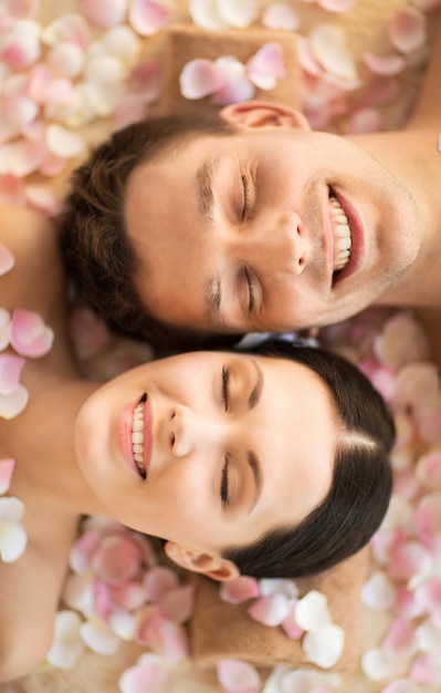 Foto rostos de casal em salão de spa deitado nas mesas de massagem
