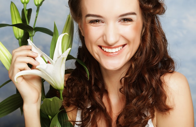 Rostro de belleza de la joven mujer con lirio blanco