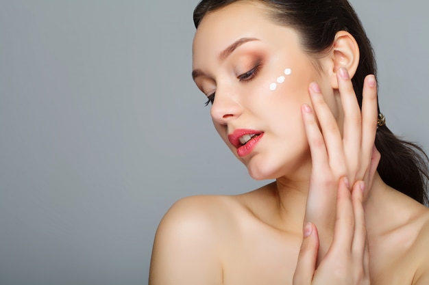 Rostro de belleza de mujer con crema cosmética en la cara