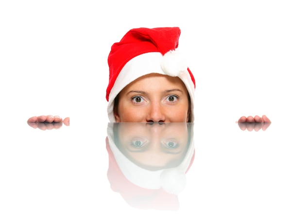 Un rostro femenino en el sombrero de Santa y su reflejo sobre fondo blanco.