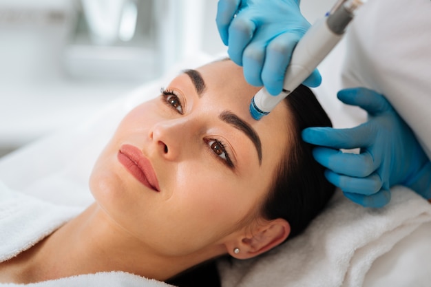 Rostro de una hermosa mujer agradable que se limpia durante el procedimiento hydrafacial