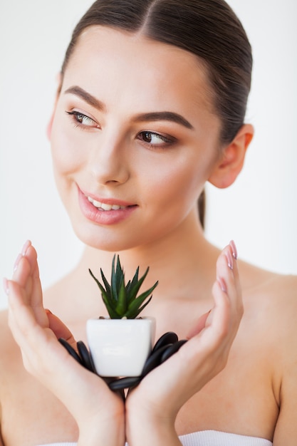 Rostro de mujer de belleza con piel sana y planta verde