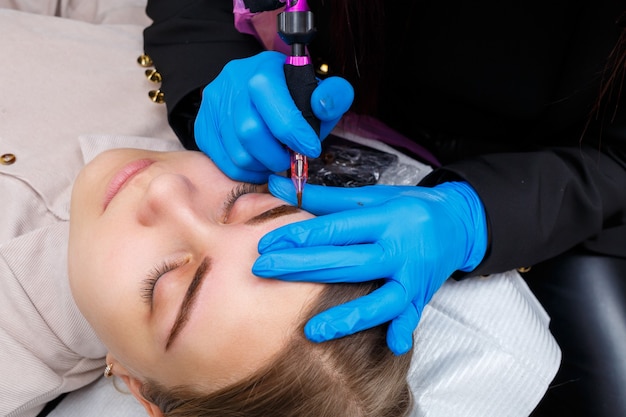 Rostro de una mujer hermosa con cejas pobladas en un salón de belleza. Maquillaje permanente para cejas. Esteticista hace tatuajes de cejas para mujeres. Procedimiento de belleza.