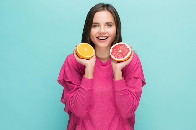 Rostro de mujer hermosa con deliciosa naranja y pomelo en el estudio