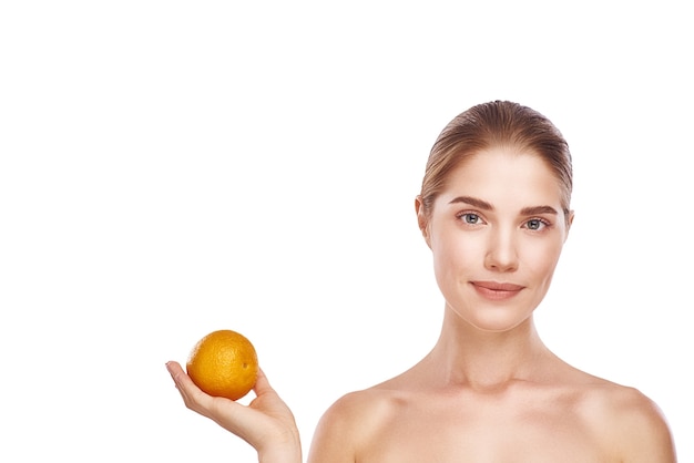 Rostro de mujer hermosa con naranja cerca de la foto de estudio sobre fondo blanco. Cabello claro, ojos grises