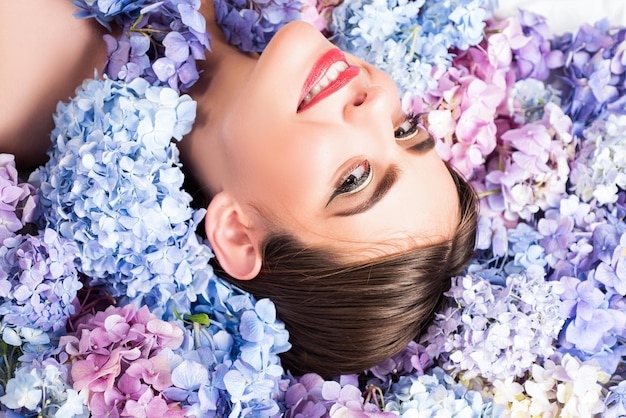 Rostro de mujer joven en hortensia floreciente en el fondo romántico y amor concepto naturaleza belleza mujer l