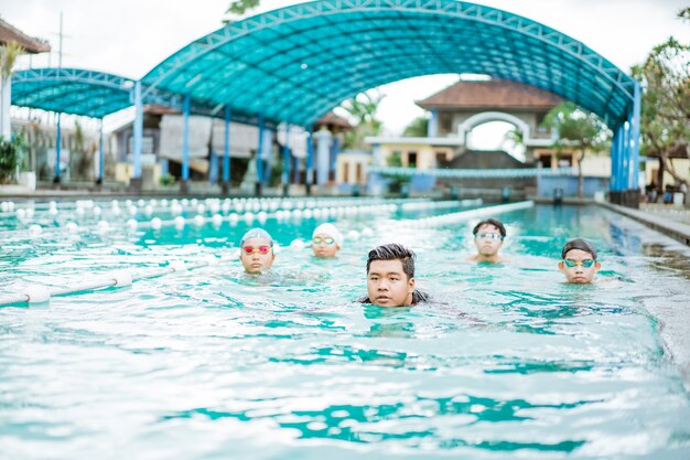 Los rostros de un instructor y cuatro adolescentes nadando en la piscina