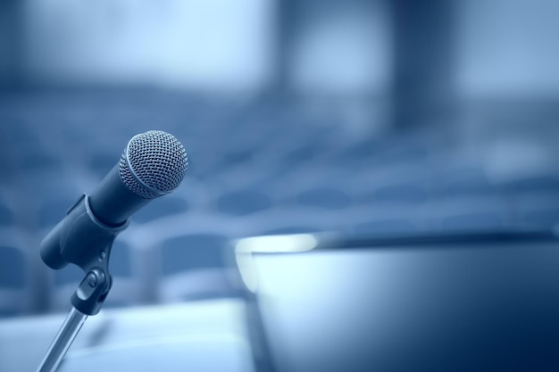 Rostrum com microfone e computador na sala de conferências com efeito de desfoque de movimento