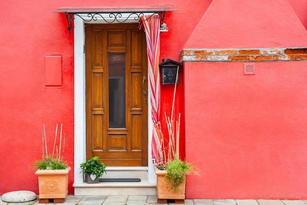 Rot gestrichene Fassade des Hauses und Holztür mit Blumen