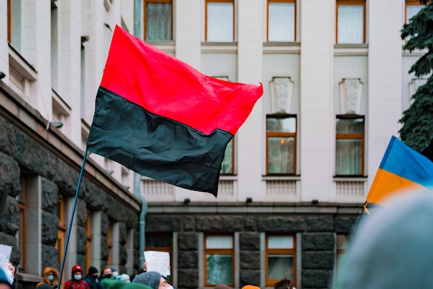 Rot-schwarzes schwarzes Banner der ukrainischen Aufständischen Armee und der ukrainischen blauen und gelben Flagge weht während des Streiks in der Nähe eines Gebäudes UPA Battle Protest Revolution Nationalistische Bewegung Riot Street