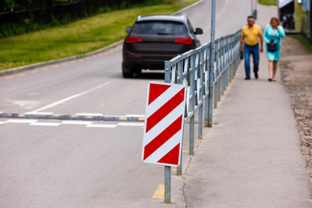 Rot-weiß diagonal gestreiftes Schild am Ende des Straßenzauns