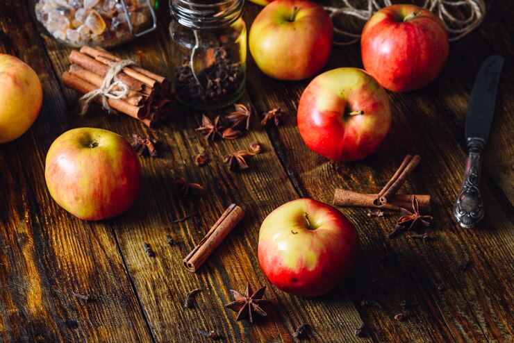 Foto rote äpfel mit verschiedenen gewürzen zum kochen von apfelkuchen.
