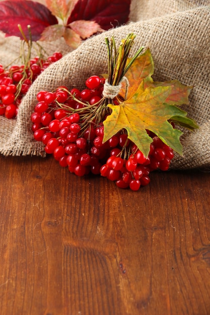 Rote Beeren von Viburnum auf Sackleinenserviette, auf hölzernem Hintergrund