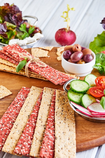 Rote-Bete- und Roggenmehlcracker mit Gemüse für die Zubereitung von Snacks auf einem Holztisch. Vegetarismus und gesunde Ernährung
