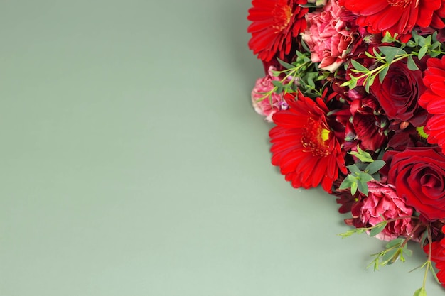 Rote Blumenstraußblume auf grünem Hintergrund mit Kopienraum. Blumenarrangement mit Rosen und Gerbera.