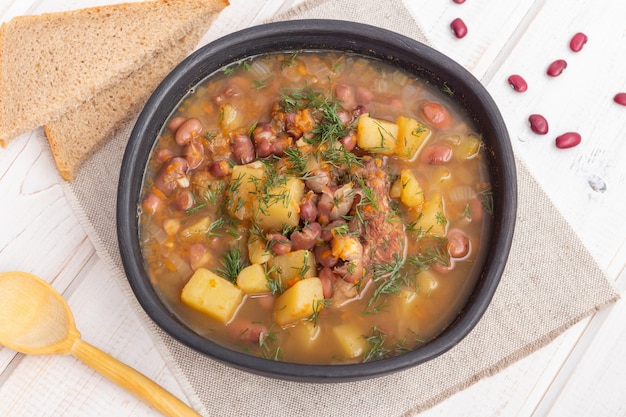 Rote Bohnensuppe mit Fleisch in einer schwarzen Tonschale