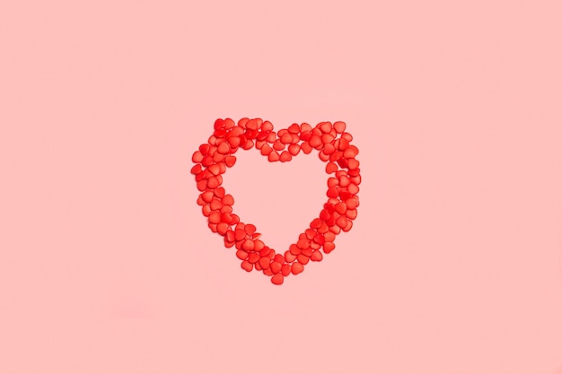 Rote Bonbons in Herzform auf rosafarbenem Hintergrund mit Kopierraum