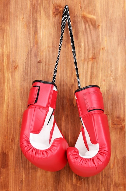 Rote Boxhandschuhe auf Holzgrund hängen