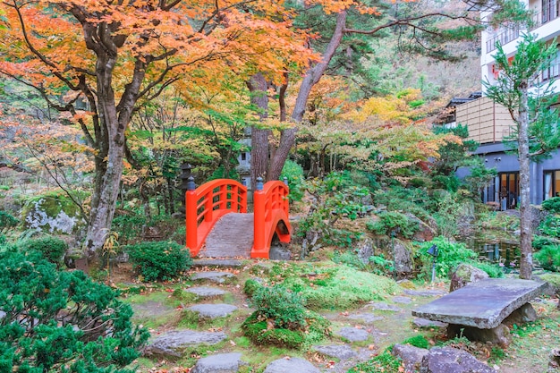 Foto rote brücke im japanischen grünen park mit herbstfarbenblättern, japanischer herbstfall