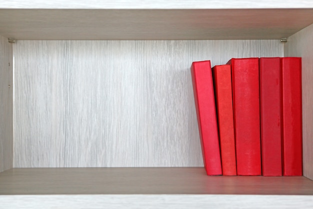 Rote Bücher in einem hölzernen Regal.