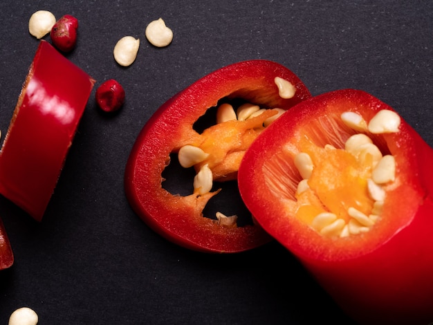 Rote Chilischoten auf einem schwarzen Tisch in Stücke geschnitten. Scharfe Gewürze, roter Chili. Zuhause kochen.