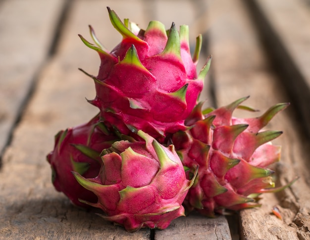 Rote Drachenfrucht oder tropische Frucht auf hölzernem Schreibtischhintergrund