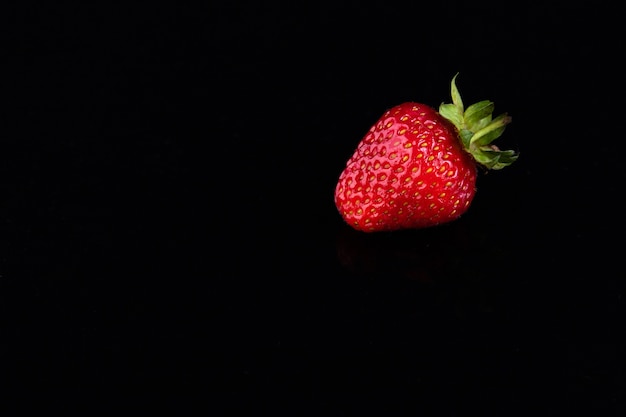 Rote Erdbeeren auf einem schwarzen Hintergrund. Süßes Lebenskonzept.