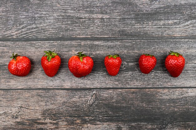 Rote Erdbeeren stellten sich vor einem dunklen hölzernen Hintergrund auf