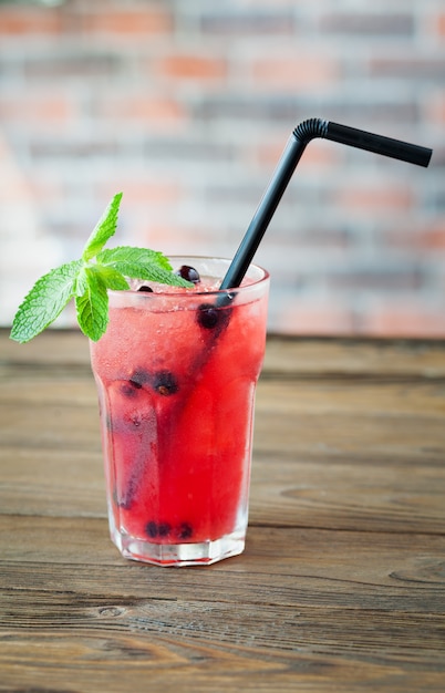 Foto rote erfrischende limonade mit beeren und eis auf einem holztisch. sommergetränk.