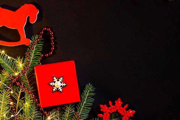 rote Geschenkbox auf dunklem Hintergrund und Tannenzweigen herum