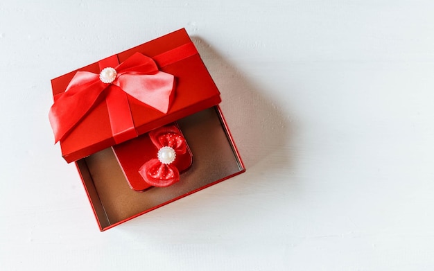 Rote Geschenkbox geöffnet auf weißem Holztisch