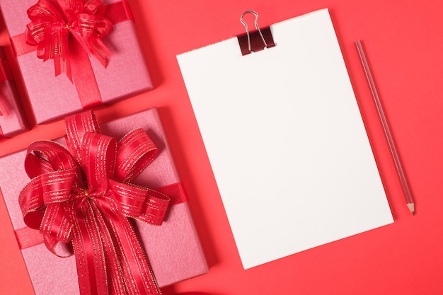 Rote Geschenkbox mit Dekorationen und Karte auf rotem Hintergrund Frohe Weihnachten und guten Rutsch ins Neue Jahr-Feiertags-Konzept
