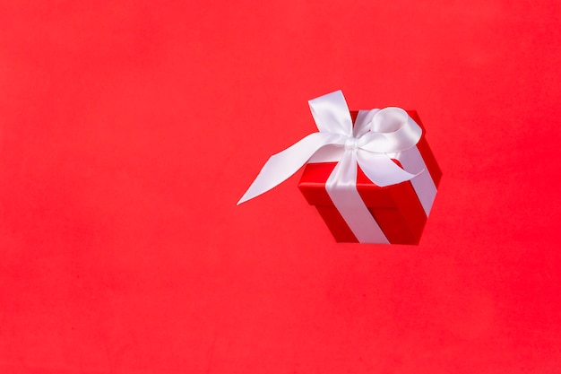Rote Geschenkbox mit Satinbandbogenfliegen auf Rot.