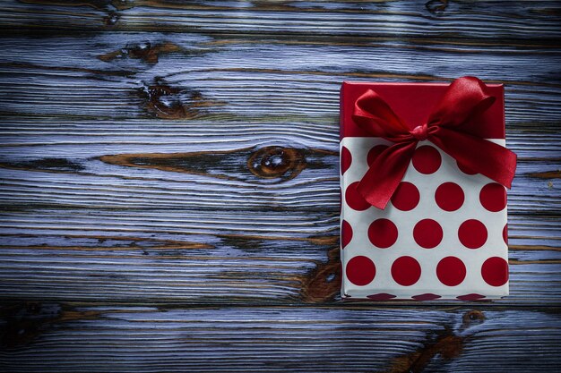 Rote Geschenkbox mit Schleife auf Vintage-Holzbrett